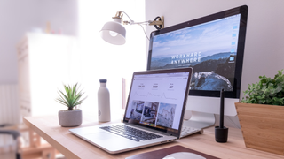 A MacBook and Mac displaying websites and images in a bright office setting