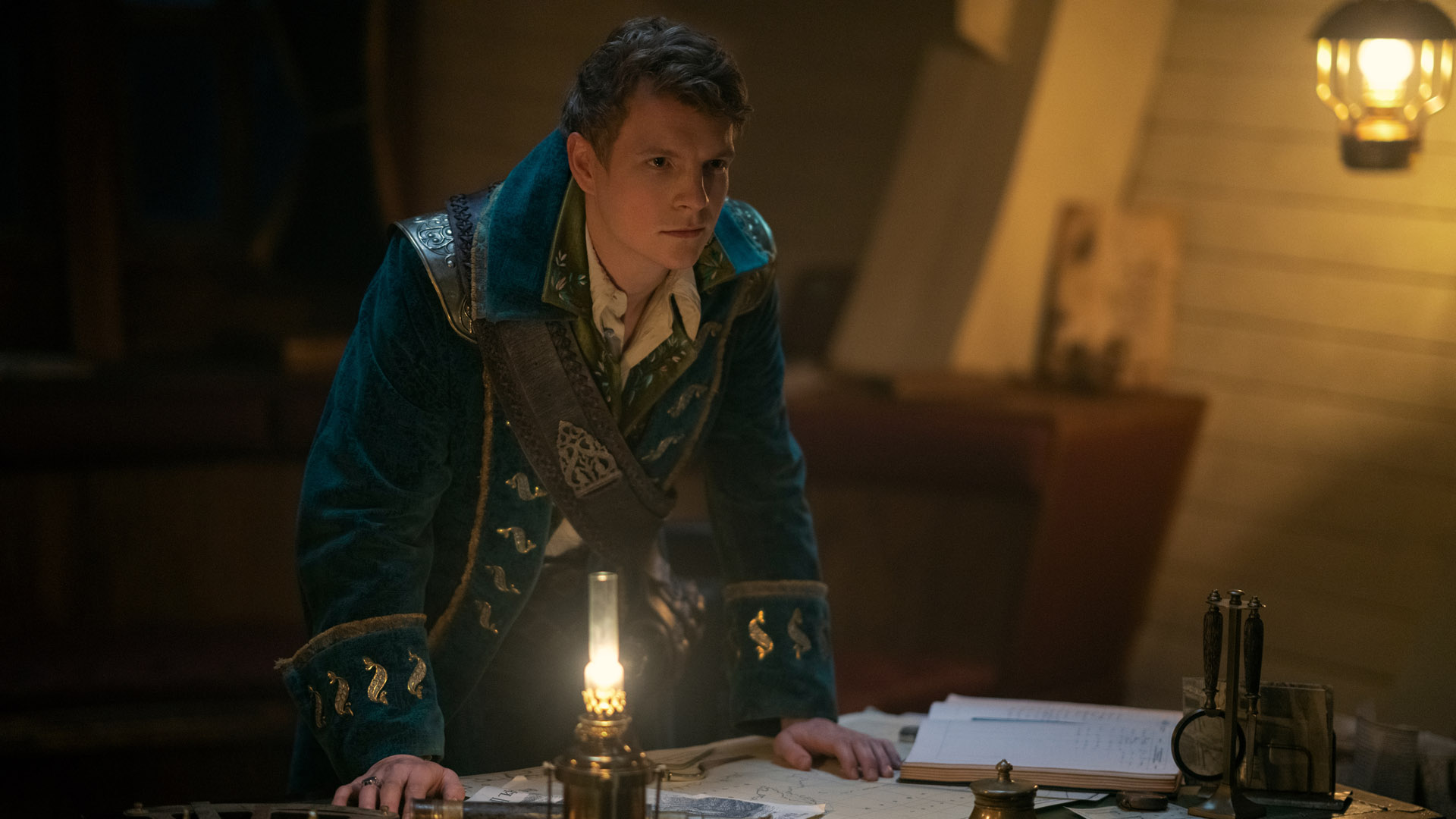 Nikolai Lantsov puts his hands on a table as he look as someone off camera in Shadow and Bone season 2