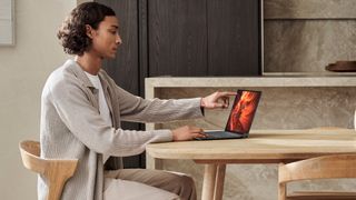 A person using an Intel Core Ultra Series 3 laptop at a wooden table in a neutrally decorated room