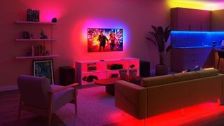 A room lit in multiple colors from various Philips Smart Lighting products, with the TV lightstrip mirroring the on-screen colors
