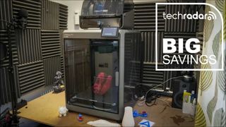 The Creality K2 Plus in our workshop during testing, next to a white TechRadar badge in the upper right corner that reads 'Big Savings'