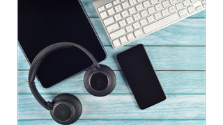 Directly above shot of bluetooth headphones, a smartphone, a tablet and a keyboard