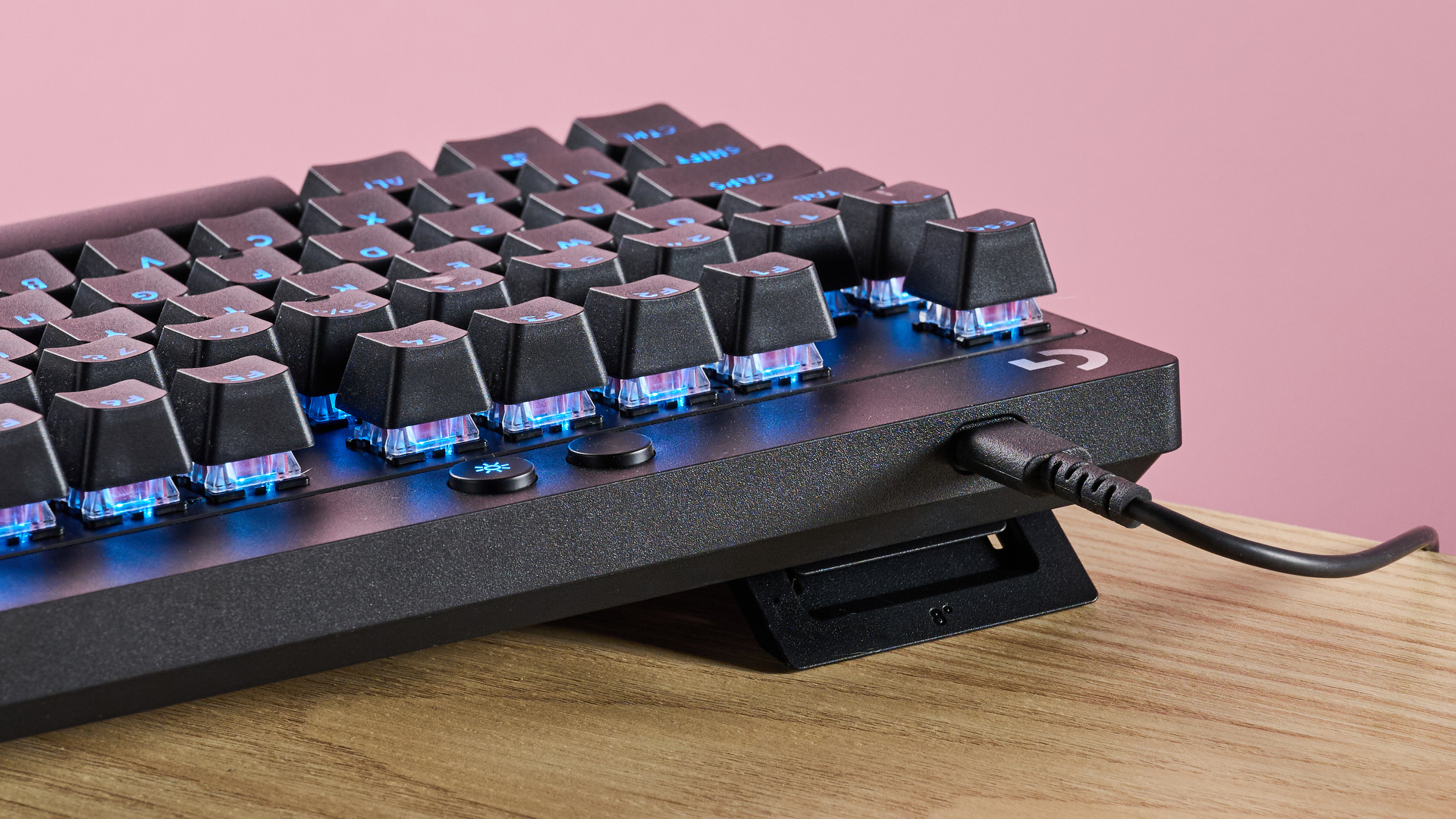 Back of Logitech Pro X TKL Rapid with USB-C cable attached, on table with pink background