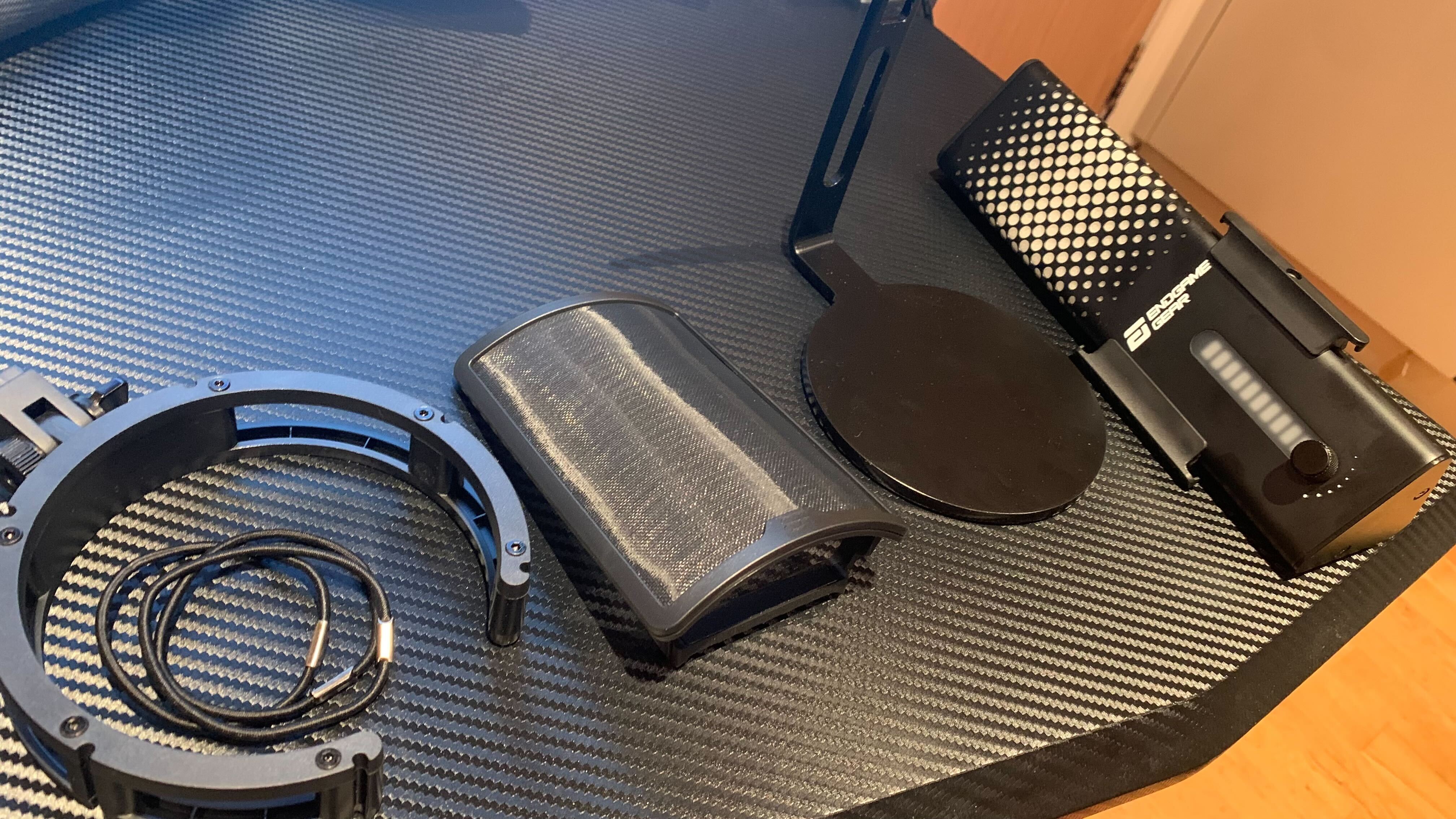 XSTRM microphone and microphone stand taken apart into its components; the shock mount and band, the magnetic pop filter, the stand and the microphone (left to right)