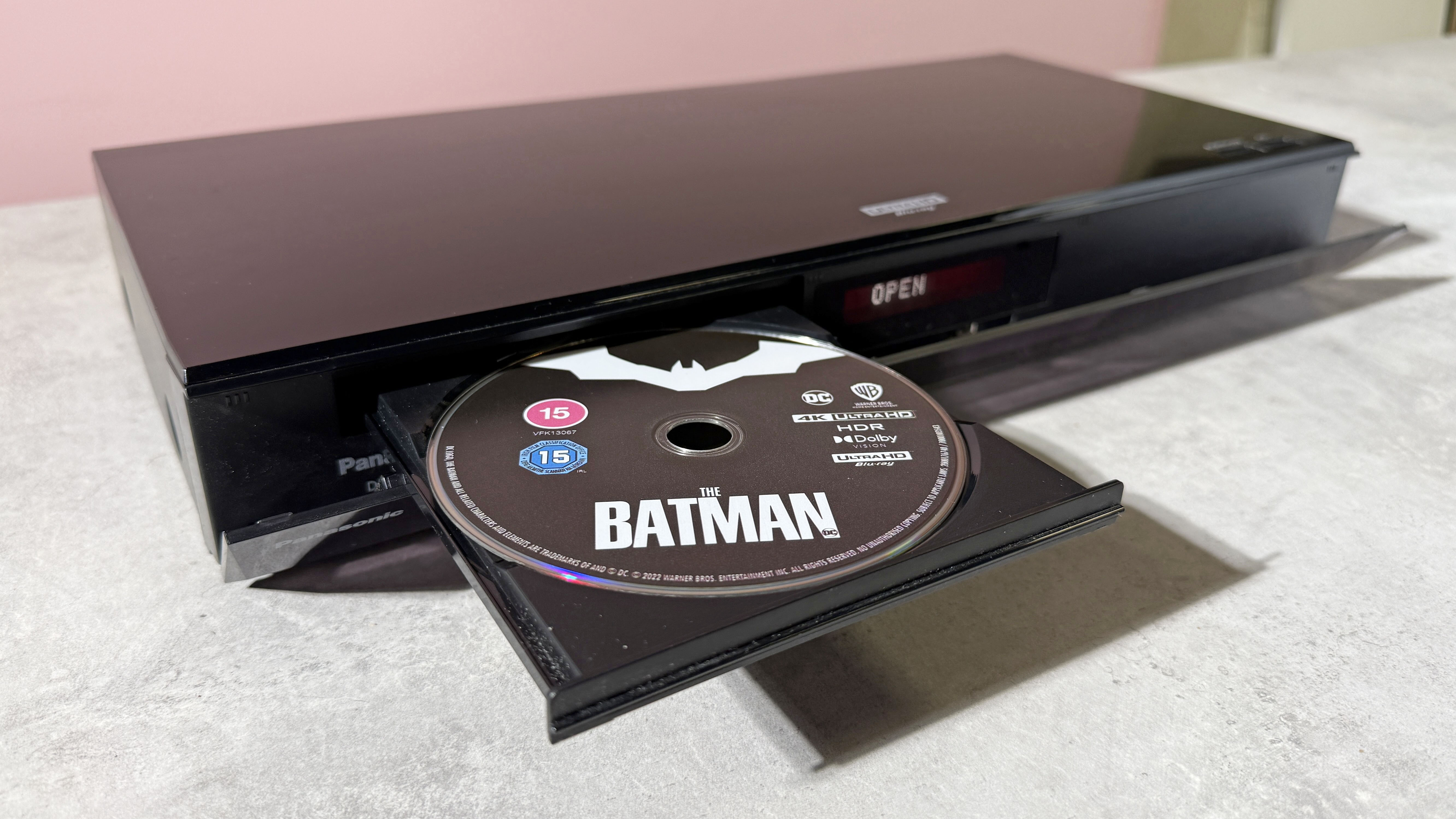 A Panasonic DP-UB820 4K Blu-ray player, with its disc tray open, and copy of The Batman on 4K Blu-ray disc in the tray