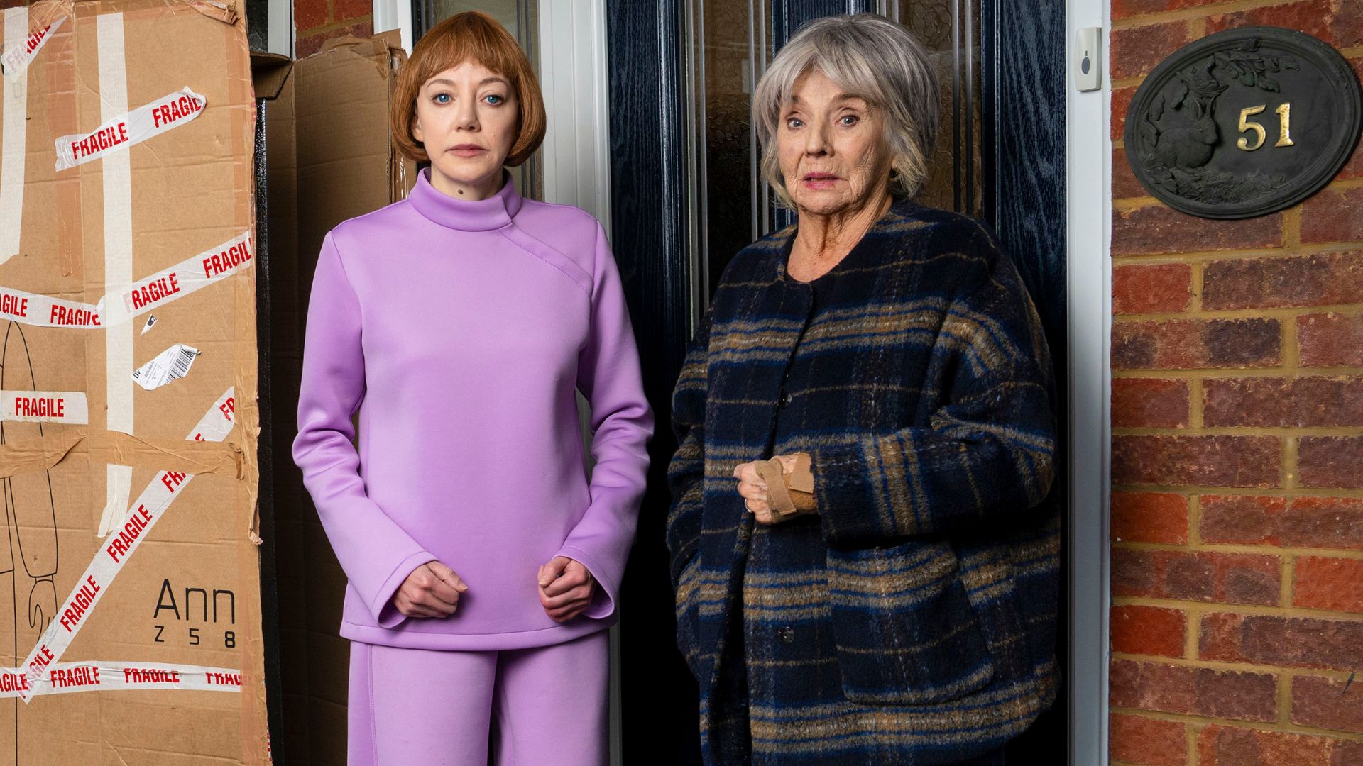 Diane Morgan and Sue Johnston stand outside of a house