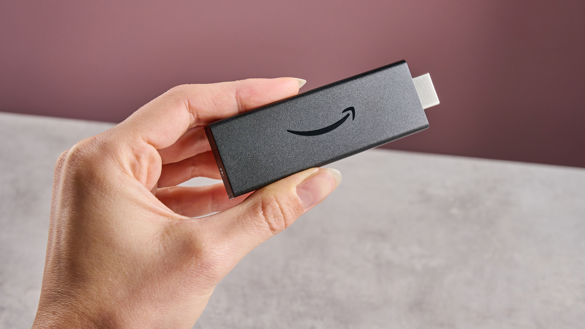 A woman's hand holds the Amazon Fire TV Stick HD.