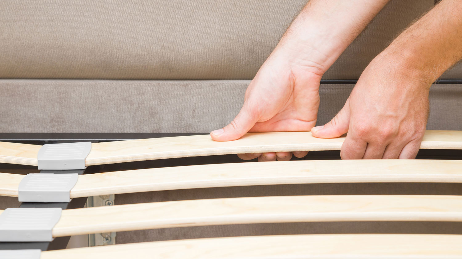 A person fixing a squeaky bed