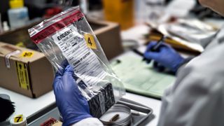 A forensic police officer examines a smartphone as evidence in a murder case at a forensic laboratory