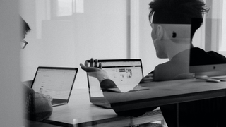 Two employees discussing work with two laptops