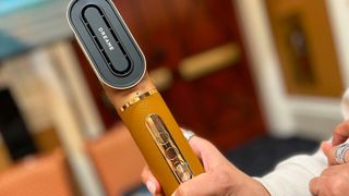 A person holds a hair styling tool with the brand name Dreame printed on it