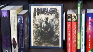 Amazon Kindle Scribe Colorsoft on a bookshelf with the cover of the Hellblazer comic open.