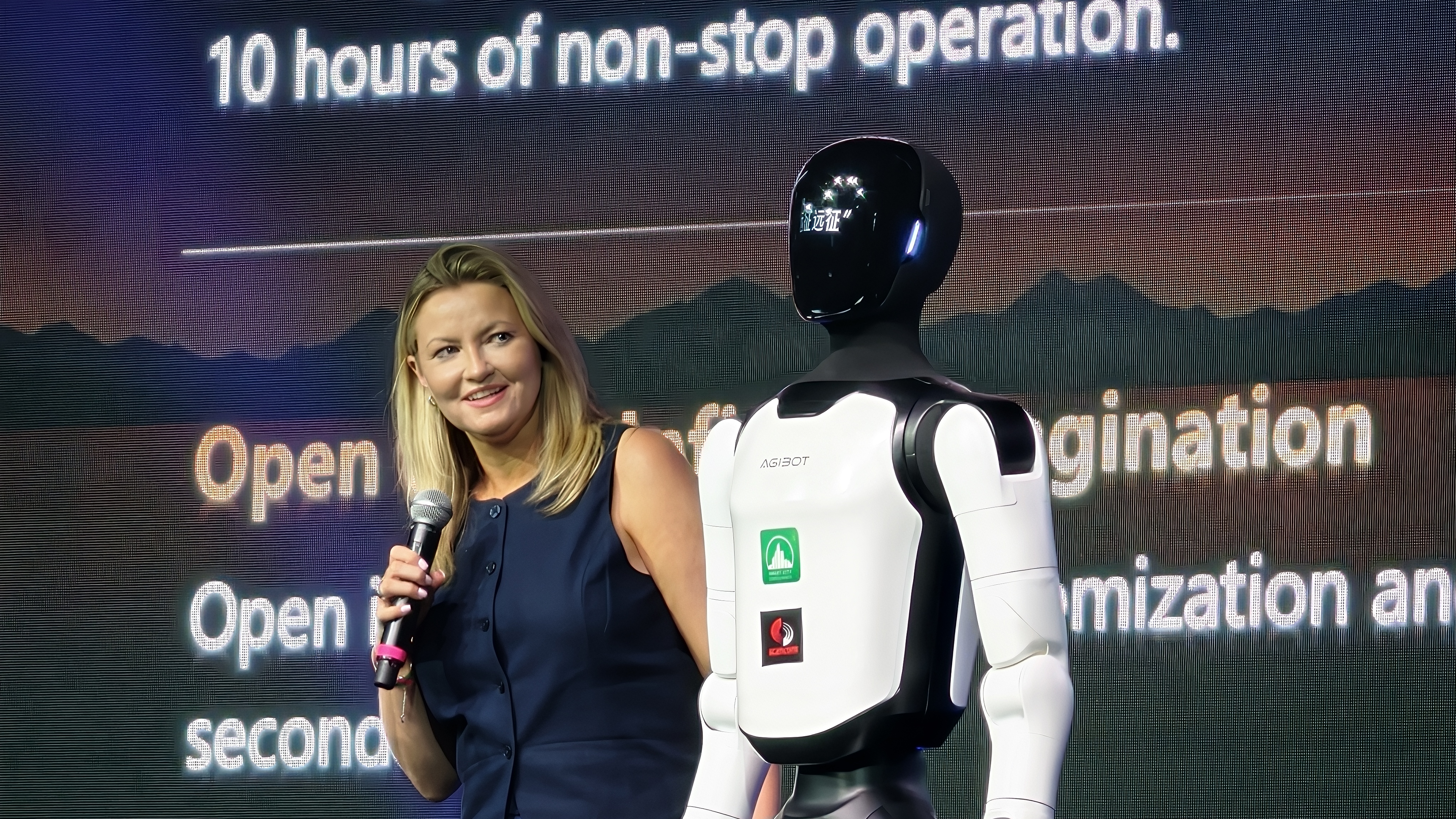 A presenter stands with the AGIBOT A3 on stage