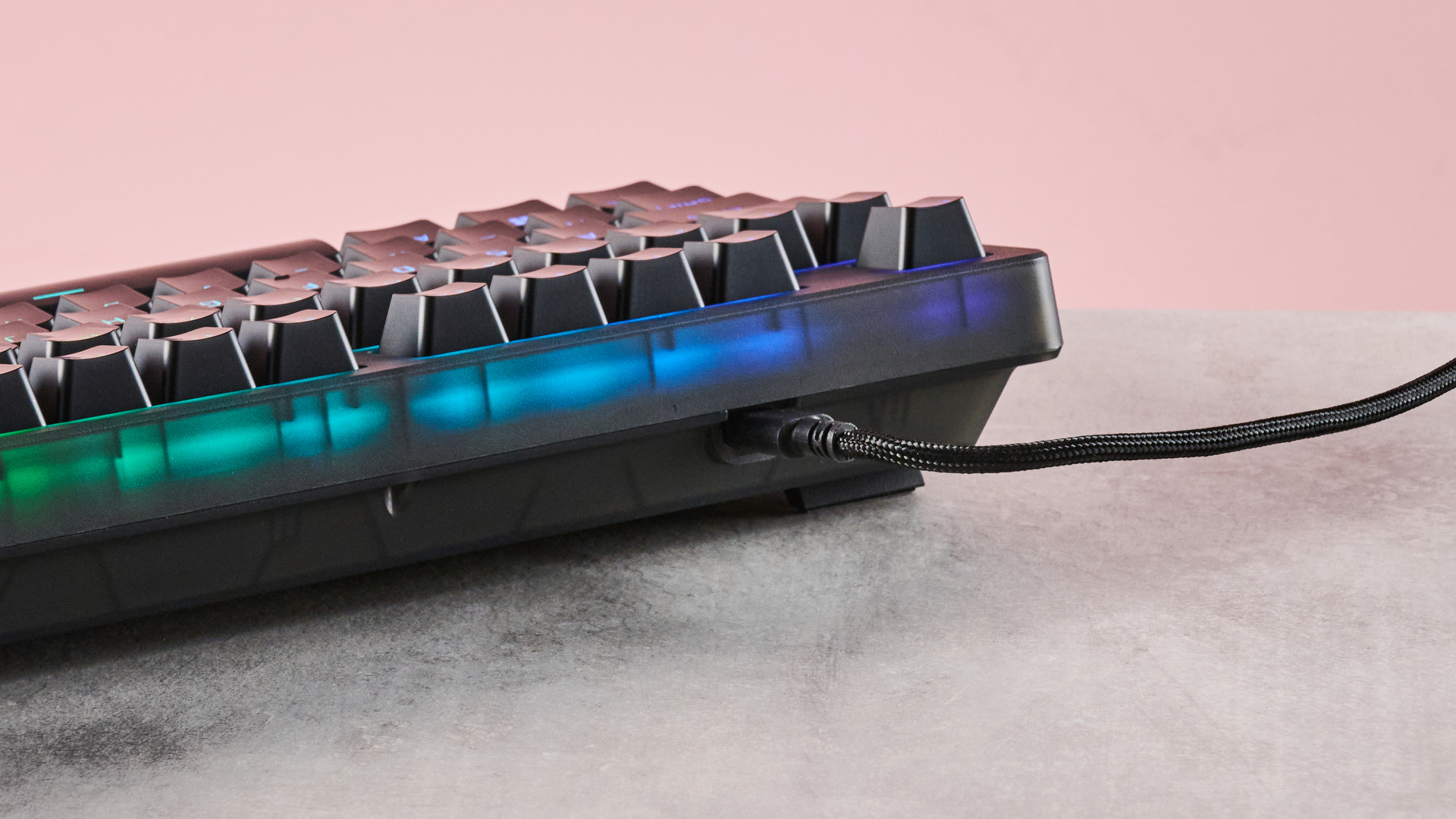 Close-up of back of HyperX Origins 2 1800 with RGB backlighting on, on a desk with pink wall in background