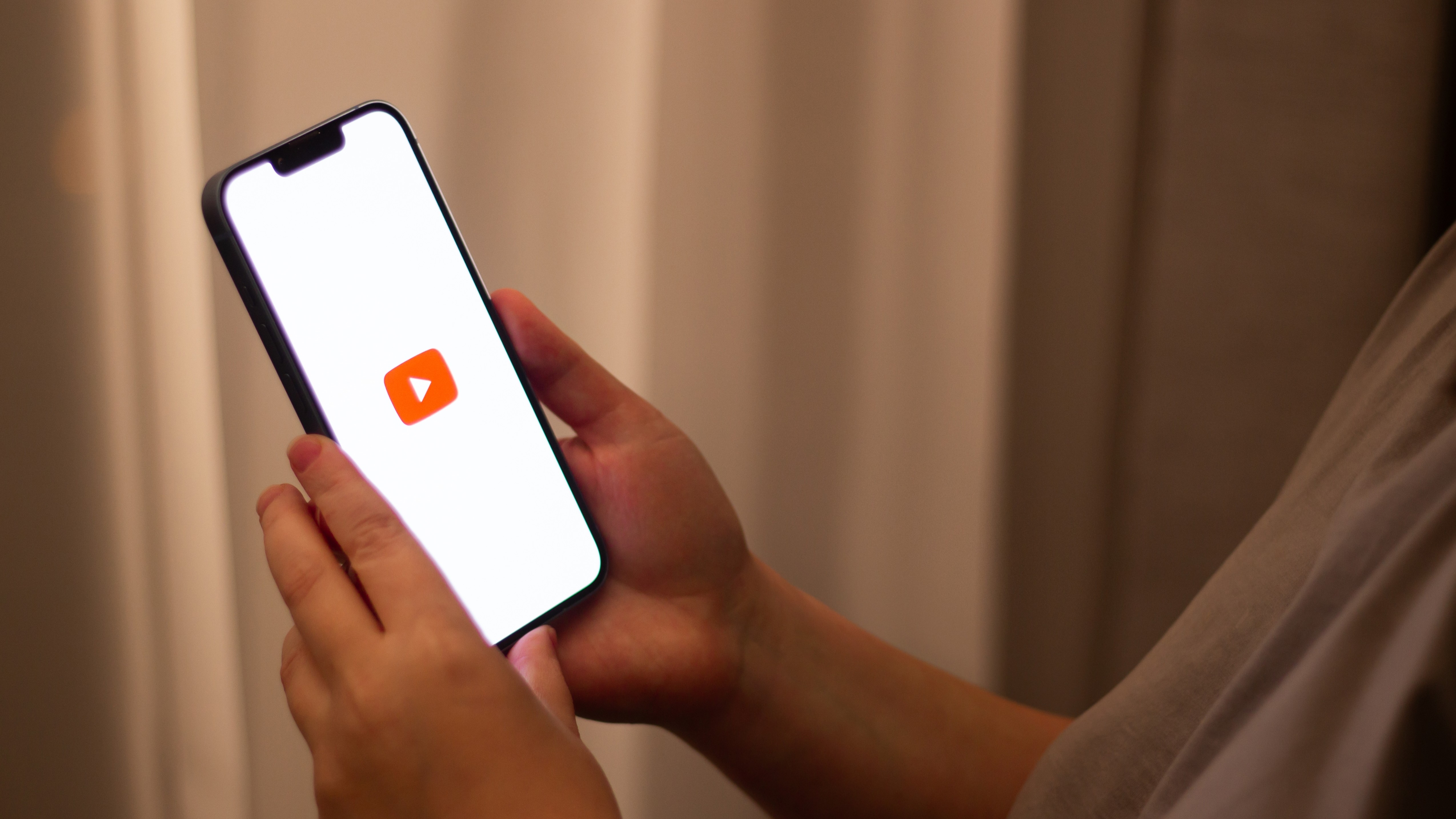 Someone holding up a smartphone displaying the YouTube app 