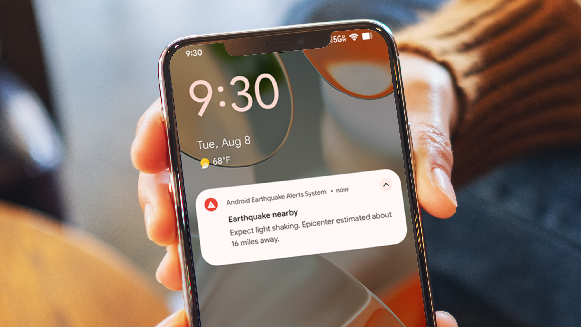 A hand holding an Android phone showing its earthquake alerts system