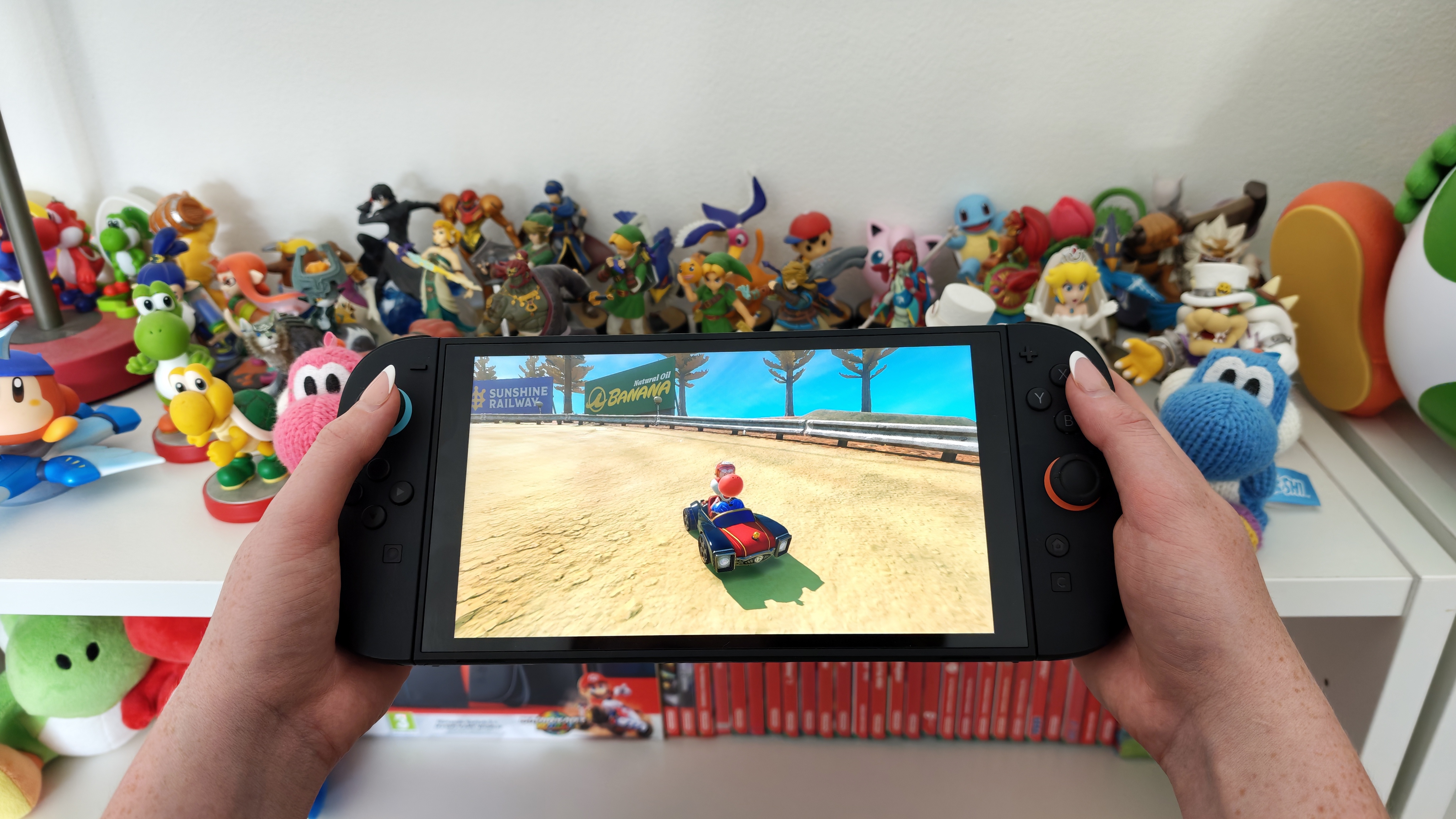 Woman playing Mario Kart World on Nintendo Switch 2 in front of amiibo figures