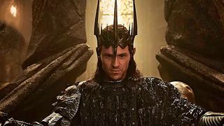 A smirking Sauron wearing his armor and sitting on his throne in The Rings of Power season 3