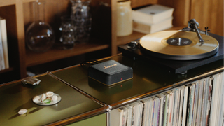 A Marshall Heddon hub atop a shelving unit full of vinyl, sat next to a record player