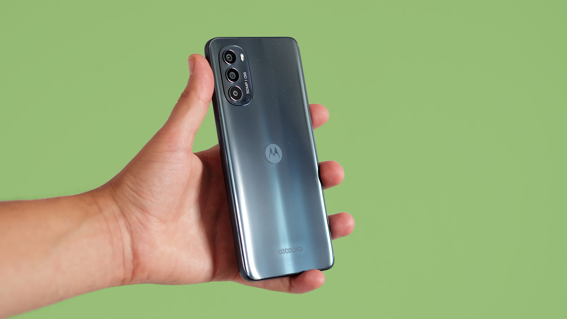 Motorola Moto G82 in hand on green background