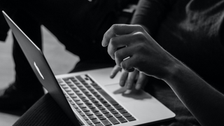 Woman's hand hovering over a laptop in black and white