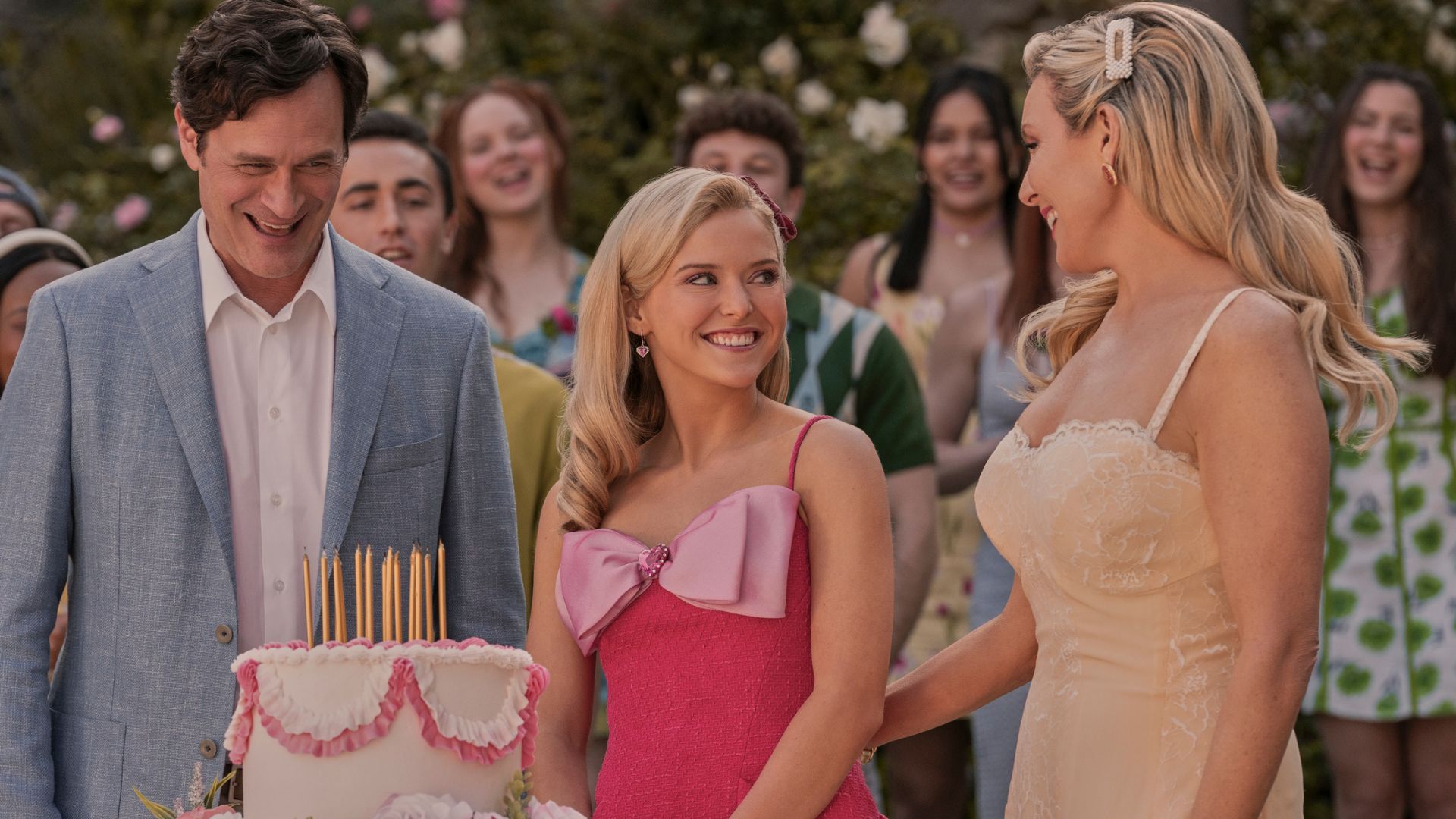 Elle stands between her parents in front of a birthday cake