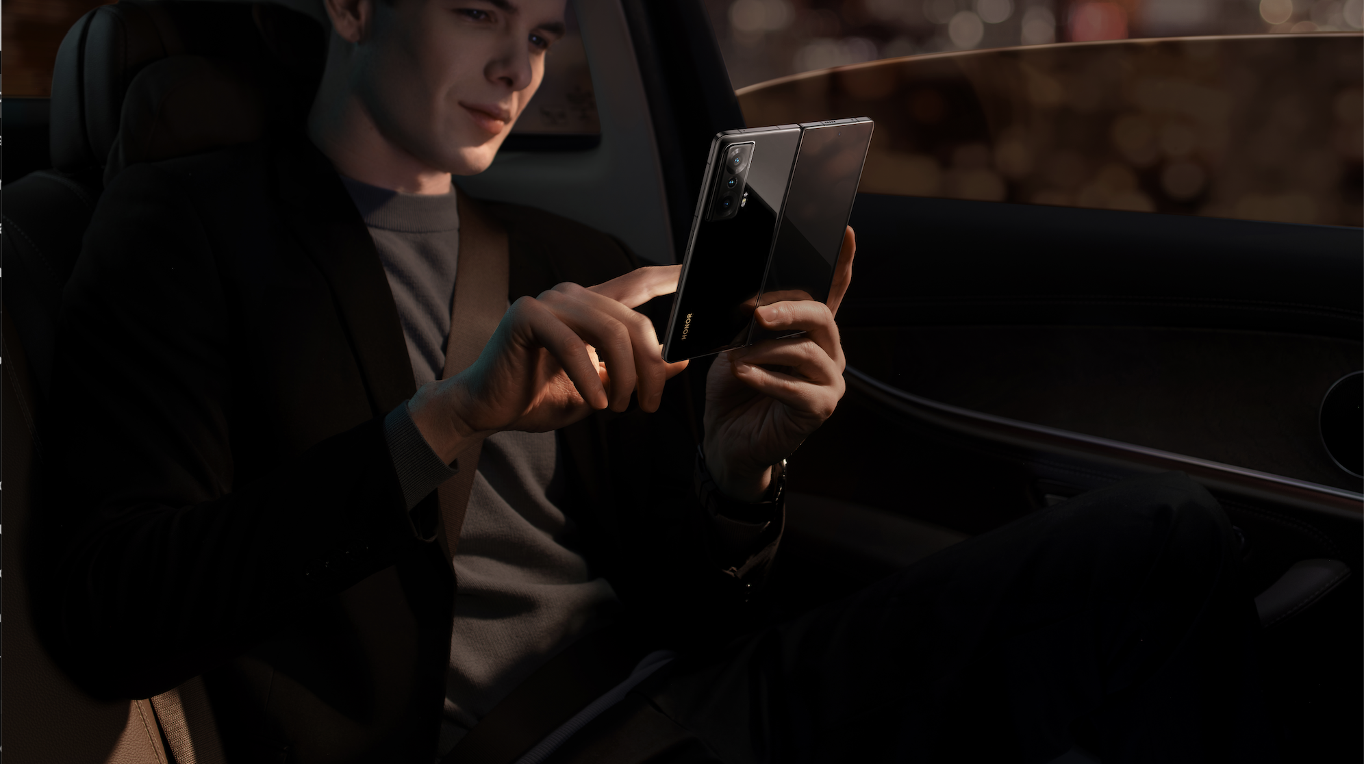 Man using honor magic vs in the bakc of a car