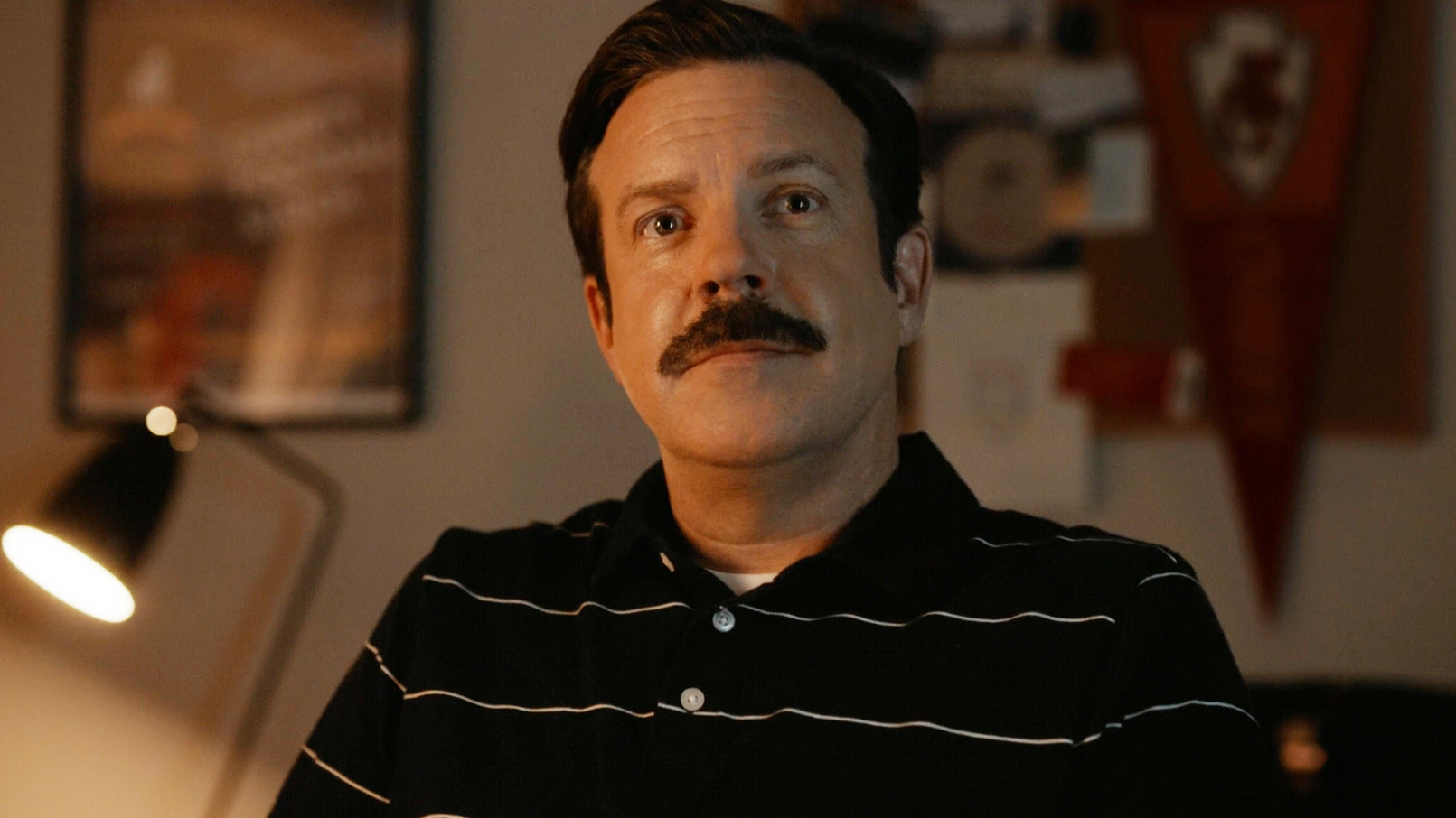 Jason Sudeikis' Ted Lasso looking at something off-camera at night in Ted Lasso season 4 episode 1