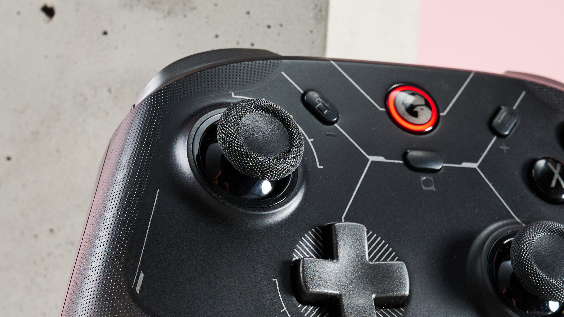 Close-up of left analog stick on GameSir Cyclone 2, with stone and pink wall in background