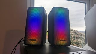 The Trust GXT 611 Wezz RGB speakers pictured on a wooden desk.