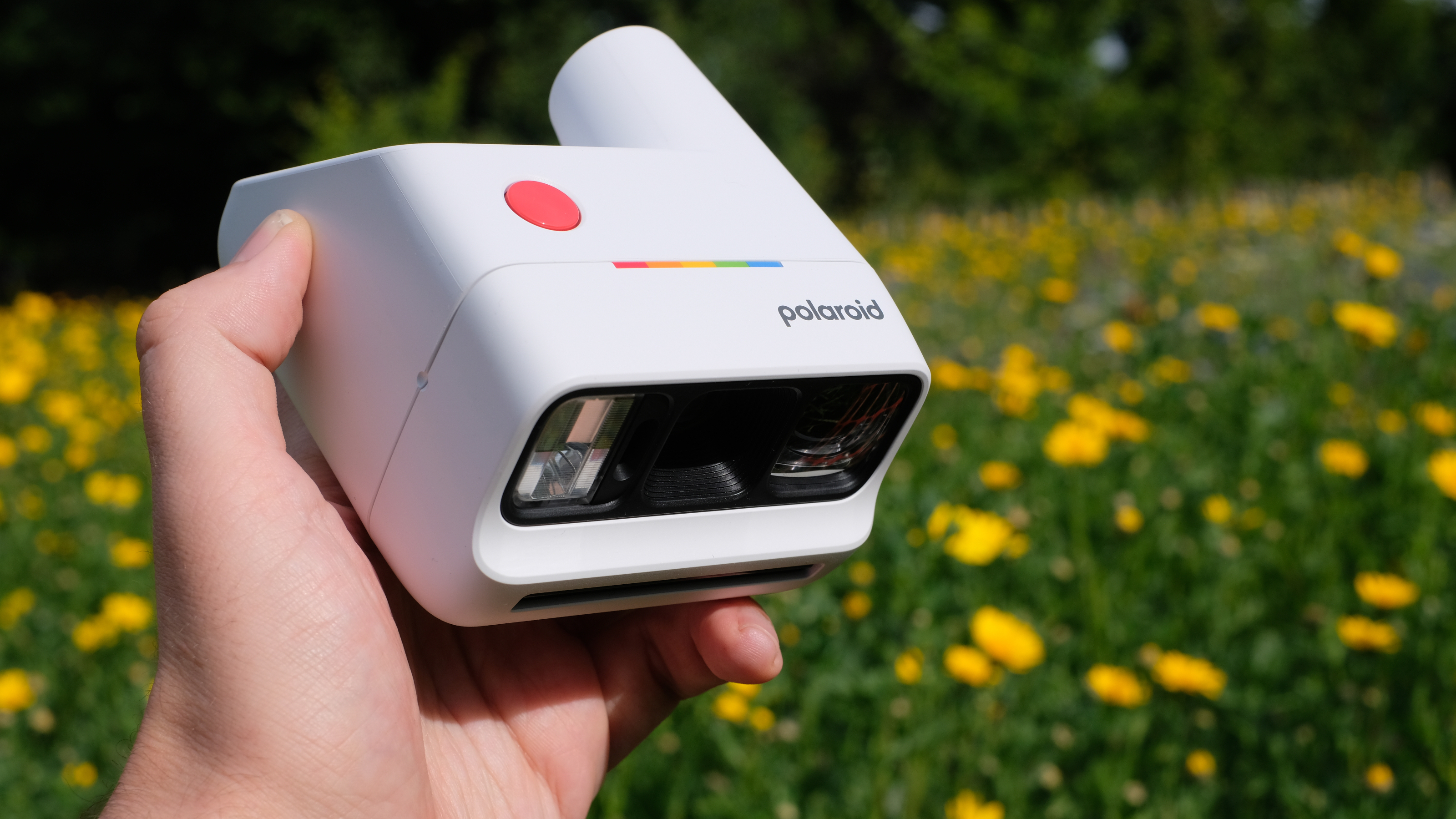 Photograph of man's hand holding Polaroid Go Gen 3 camera in white