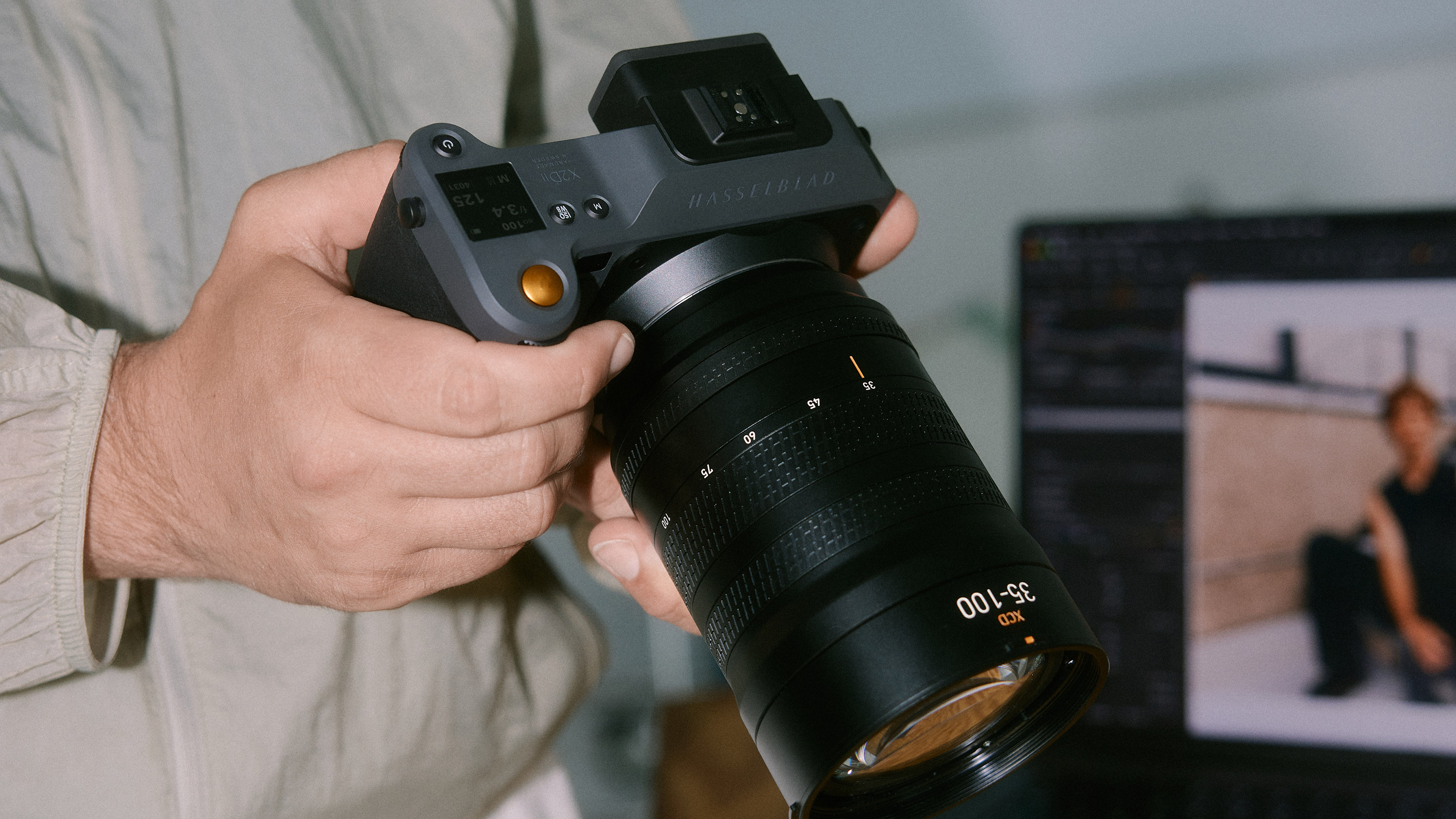 A Hasselblad camera in photographer's hands, alongside a Macbook with the Capture One software on the display