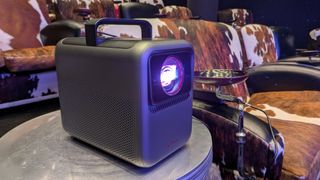 Anker Nebula X1 on stand next to patterned chair 