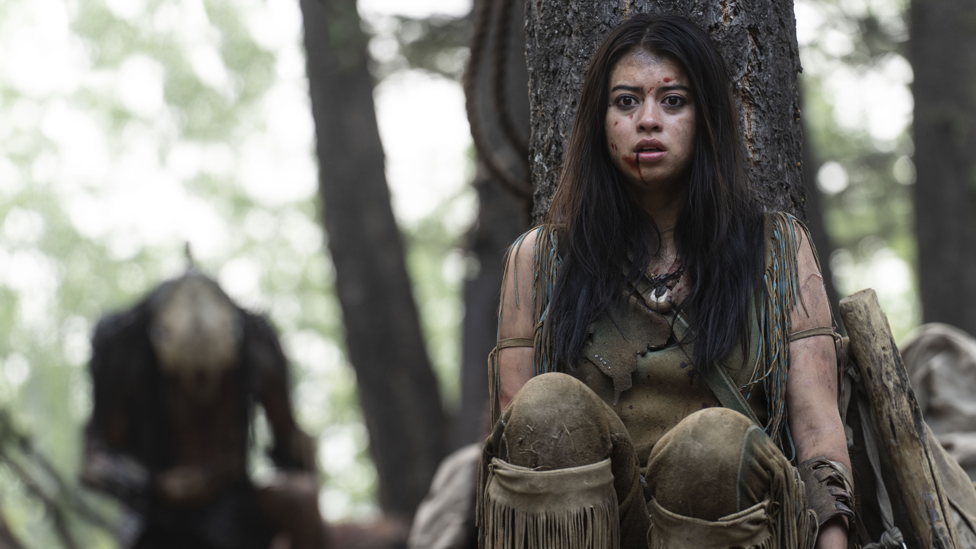 Amber Midthunder's Naru hides from the Predator behind a tree in Hulu/Disney Plus movie Prey