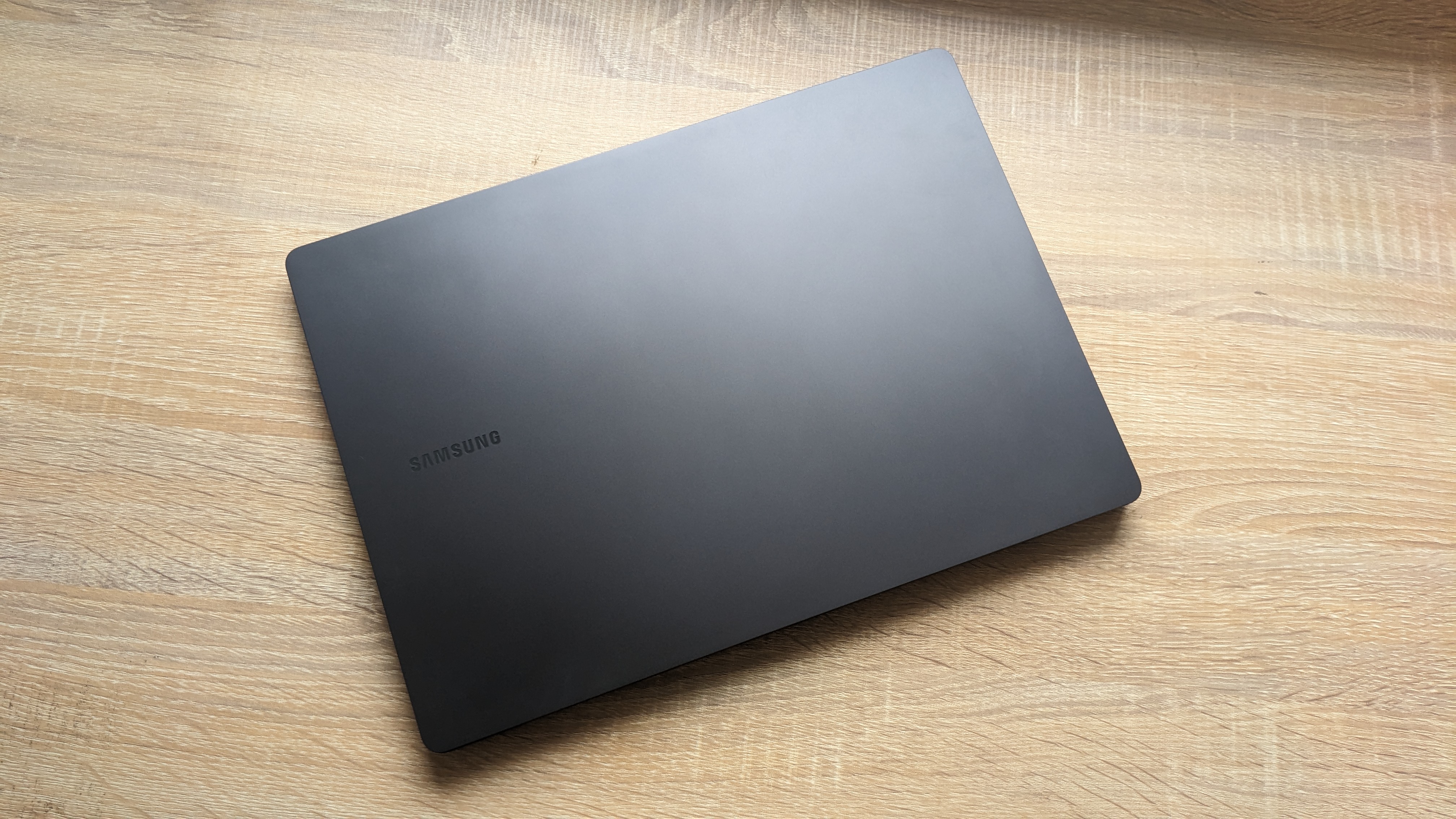The Samsung Galaxy Book3 Pro 14-inch laptop pictured atop a wooden desk.