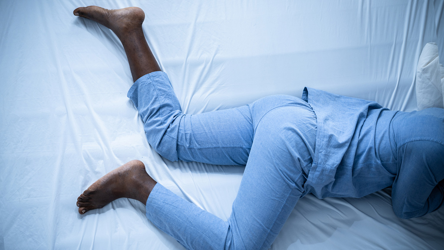 A person lying in bed with restless legs syndrome