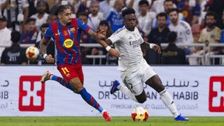 Vinicius Junior of Real Madrid is chased by Raphinha of FC Barcelona an El Clasico match.