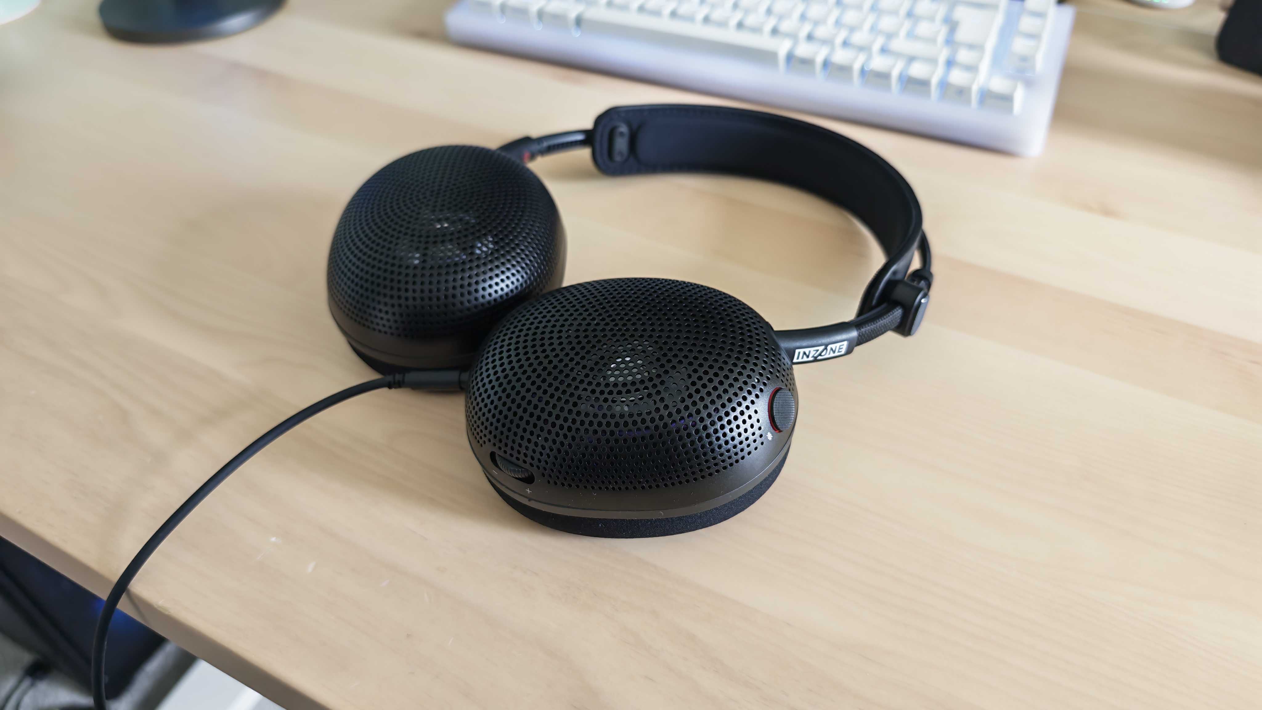 A photo of the Inzone H6 Air gaming headset positioned above a wooden desktop surface.