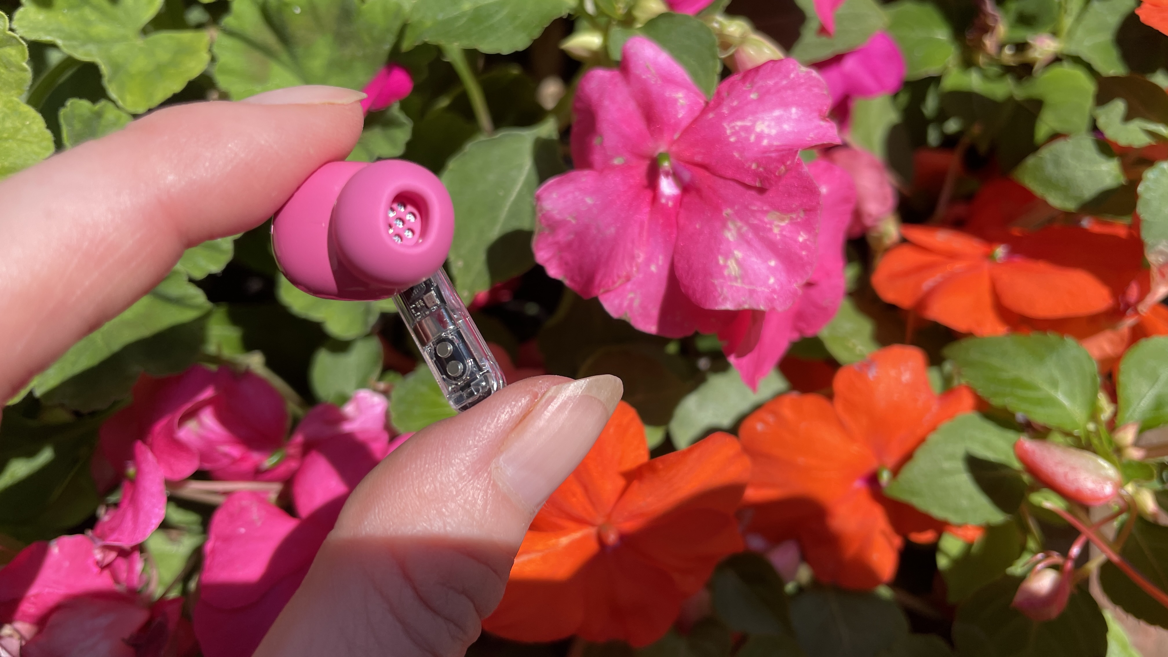 Nothing Ear (3a) on a floral background, with pink, red and yellow flowers