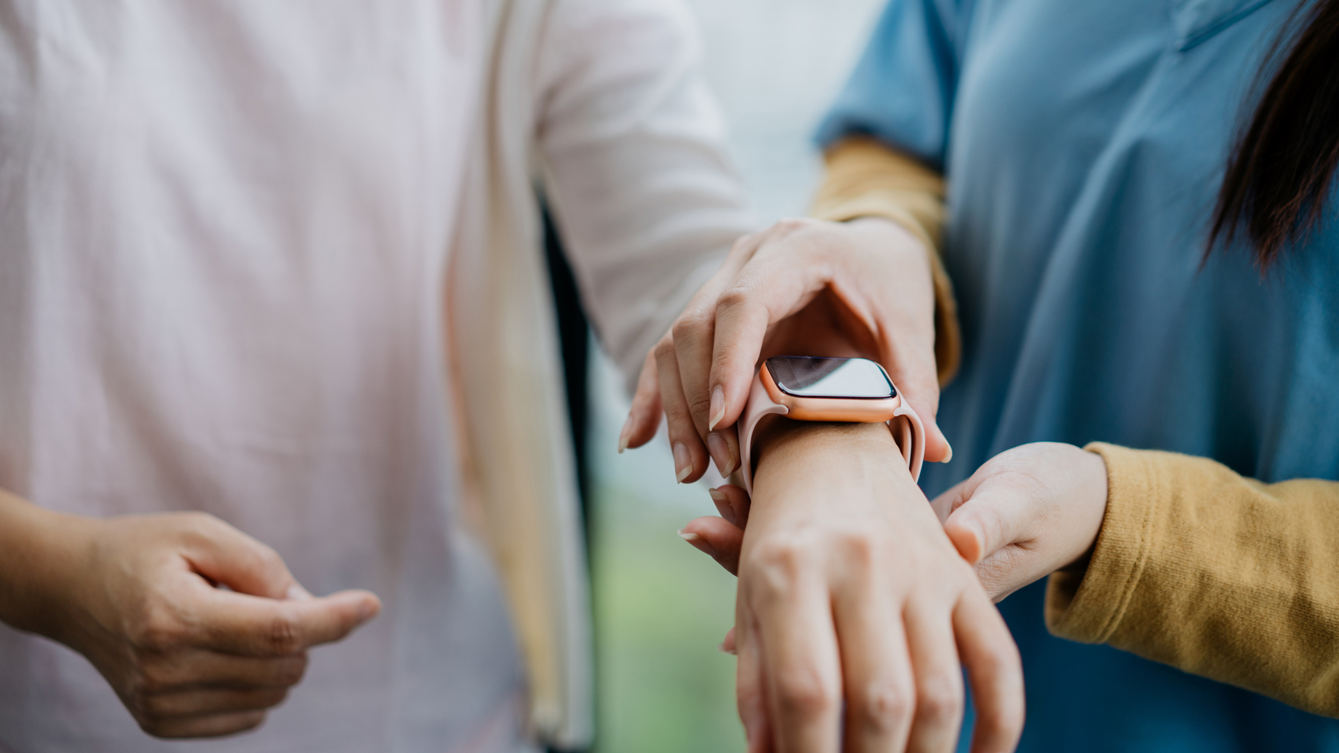 Image of one person checking another persons fitness tracker