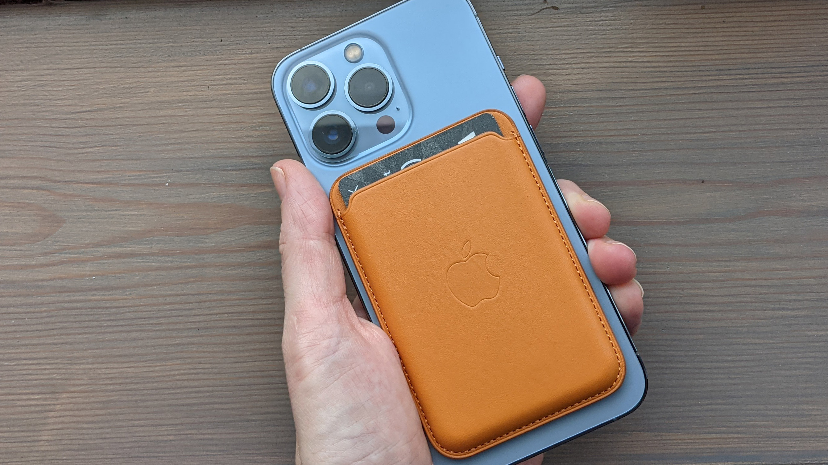 The iPhone Leather Wallet with MagSafe on the back of an iPhone 13 Pro in blue