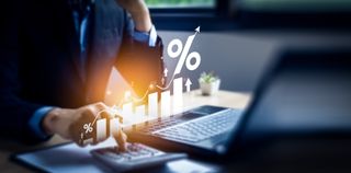 A small business owner calculating income and return on investment in percentage using a calculator from a home office.