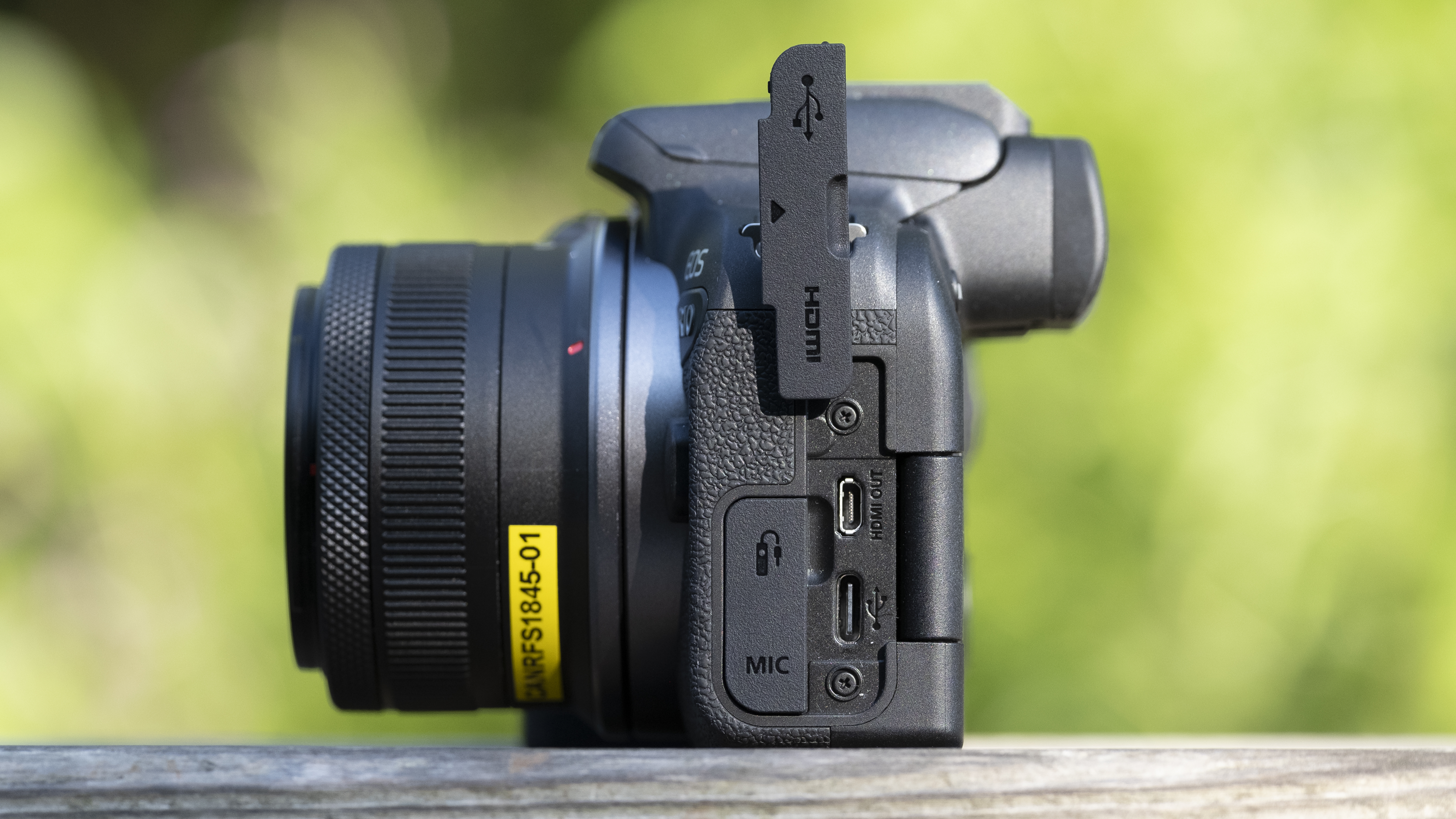 The Canon EOS R10 camera sitting on a wooden bench