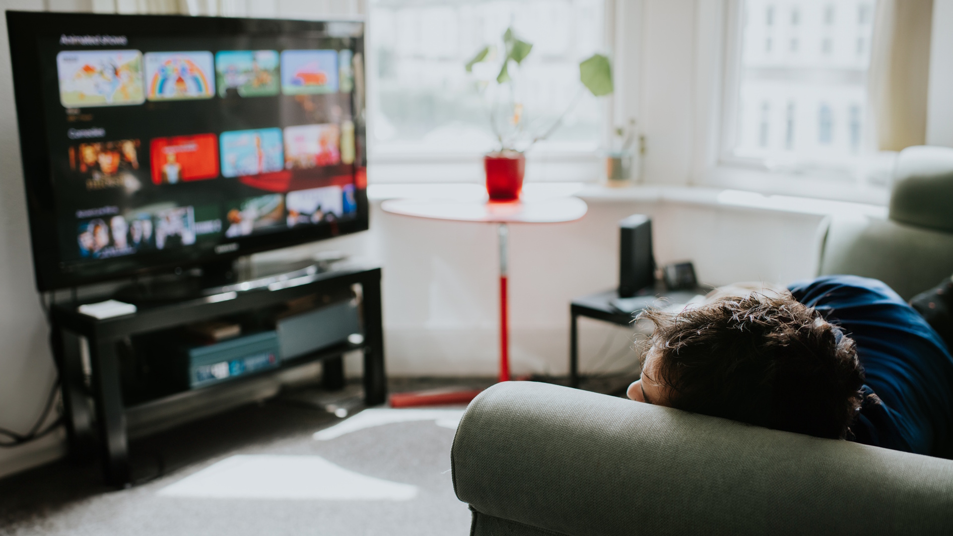 A person relaxes on a comfortable couch choosing a programme on a streaming service.