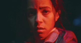 A close up of Lou Llobell in Passenger, where she is lit by a red light