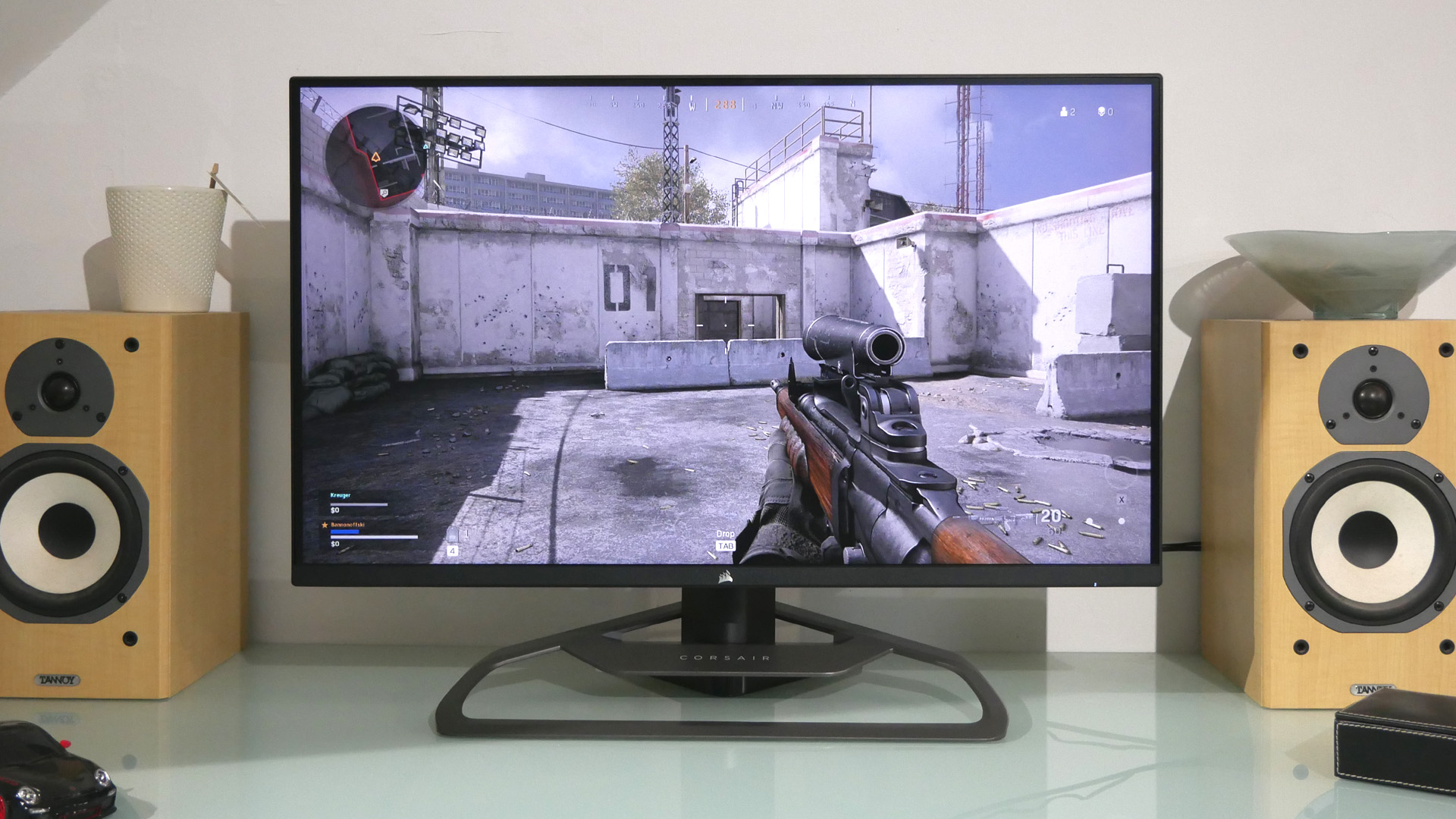 Corsair Xeneon 32QHD165 on a desk with a glass top bordered by two bookshelf speakers
