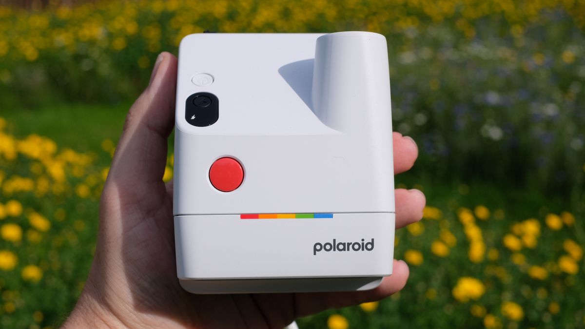 Photograph of man's hand holding Polaroid Go Gen 3 camera in white