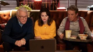 Steve Martin, Selena Gomez and Martin Short sit on a couch looking at a laptop, with a tray of food on Short's lap