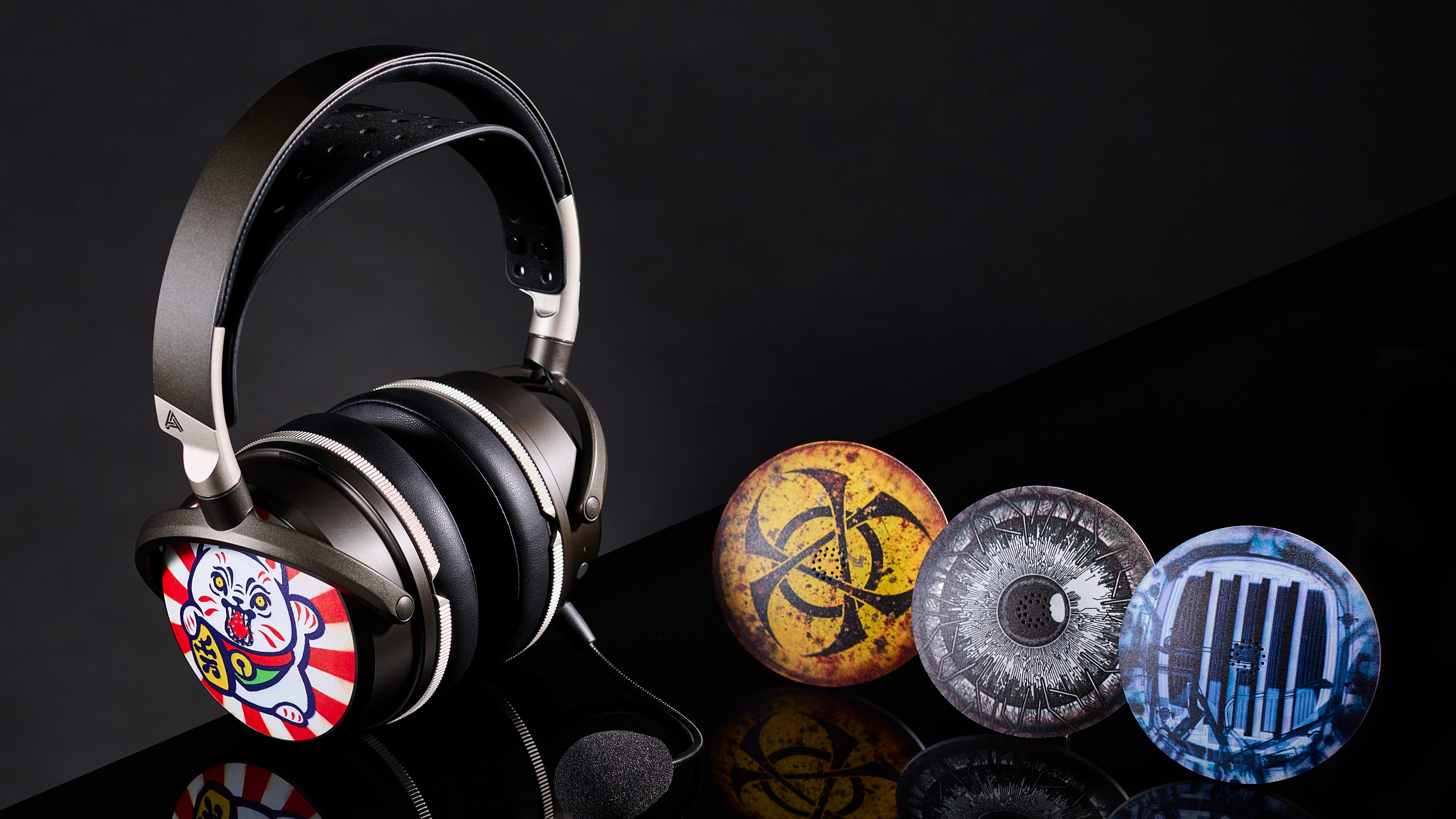An Audeze Maxwell 2 gaming headset on a black surface accompanied by four of the new ReSkin earcup designs.
