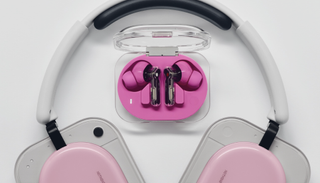 Nothing Ear (3a) on a table with Nothing Headphone (a) below, both in pink to show the difference in colorways
